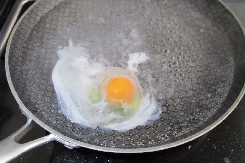 Crack the egg and drop it into the water from just above the surface of the water. 